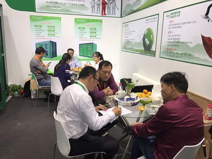 展會訪客在洽談區(qū)與薩震空壓機工作人員交流